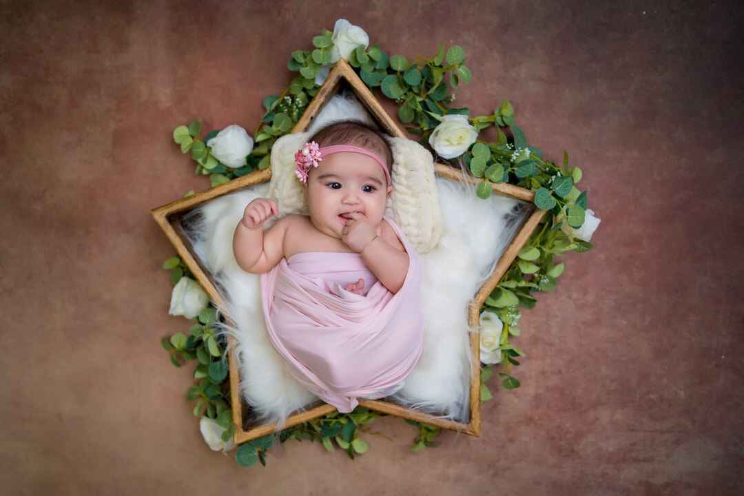 Baby girl in a pink dress, sleeping in a fluffy star tub for a baby photoshoot.